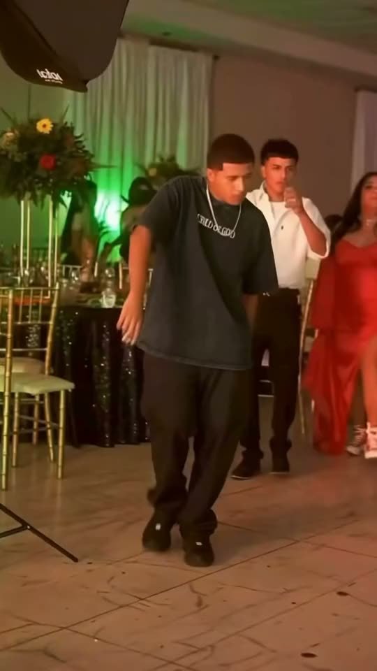 Dancer in a black tee and baggy trousers doing the Dime Dime Baby dance at a party